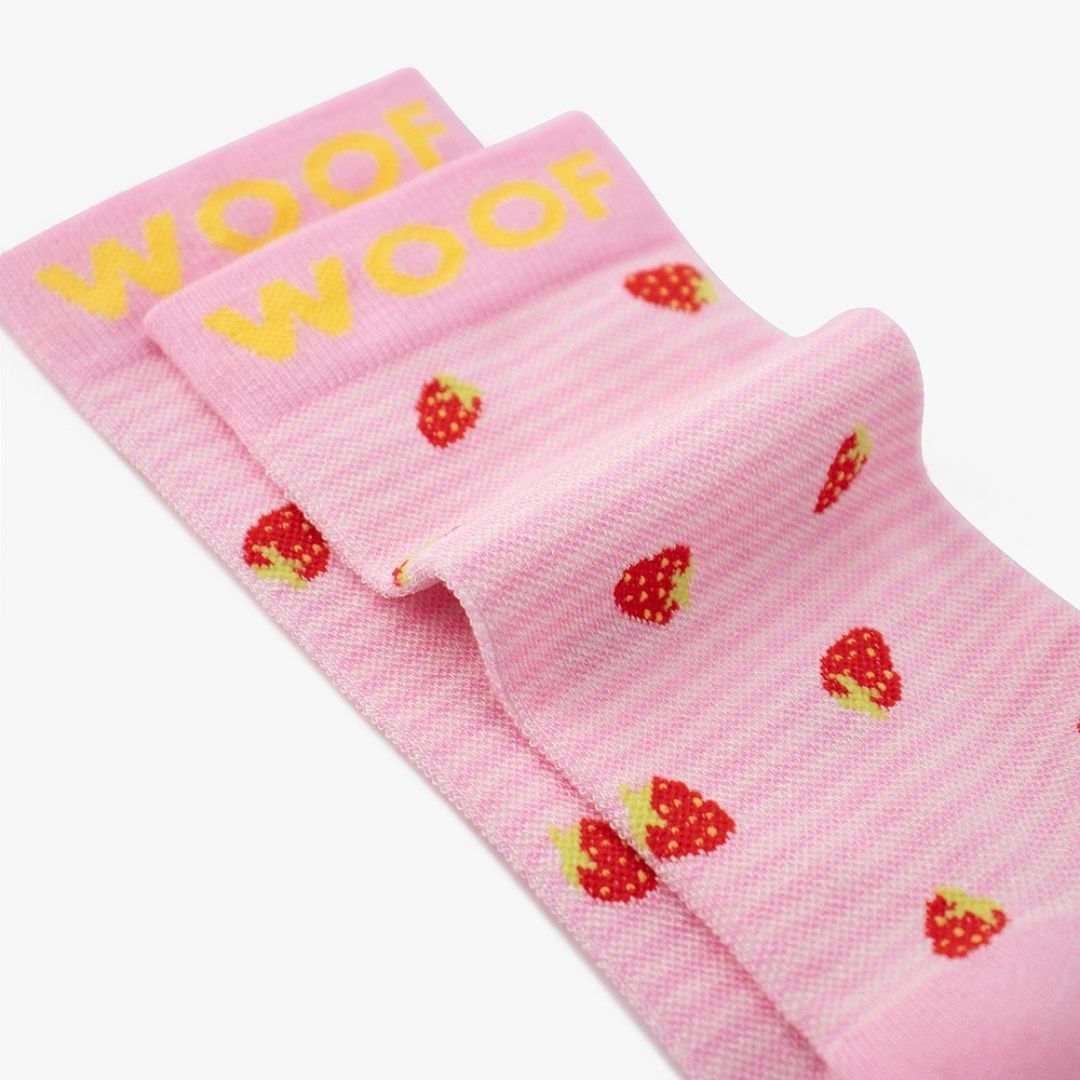 A Strawberries Bamboo Crew Compression Socks folded neatly to highlight the yellow woven "WOOF" cuff bands and the strawberry knit pattern layout.  